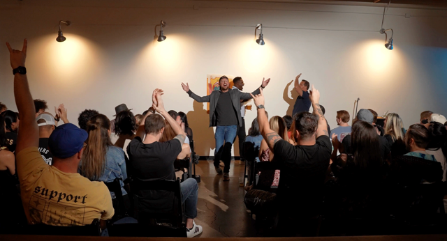 Host with arms wide as the crowd throws their hands up at Arizona After Dark