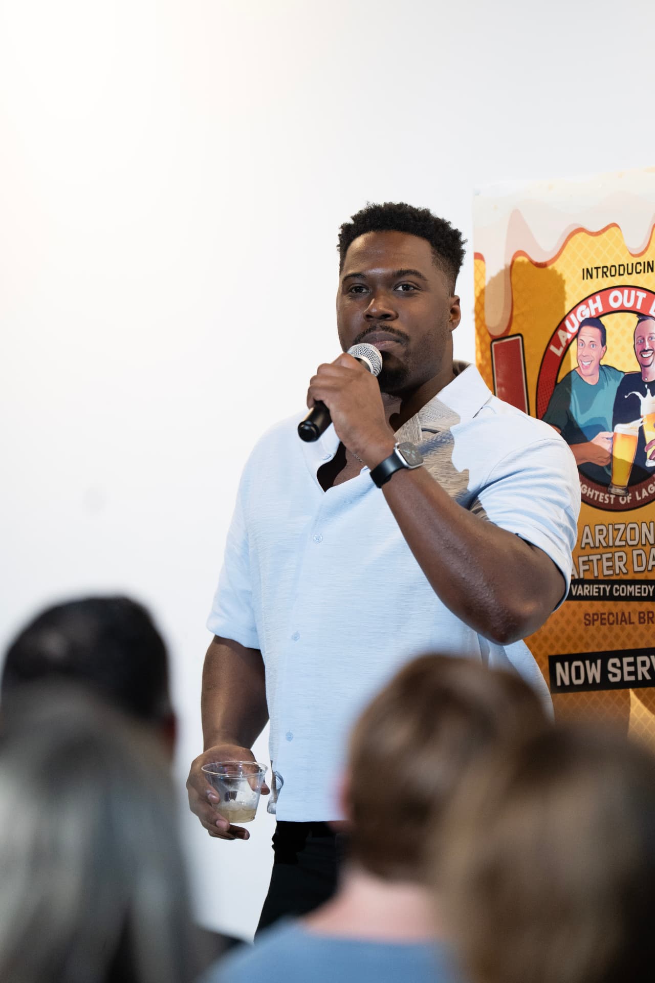 Comedian performing beside the LOL Beer poster