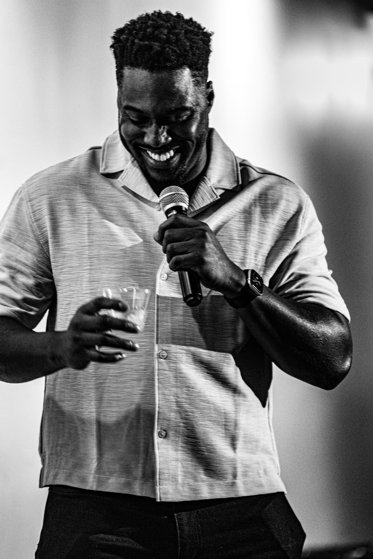 Black and white shot of a comedian grinning at the mic