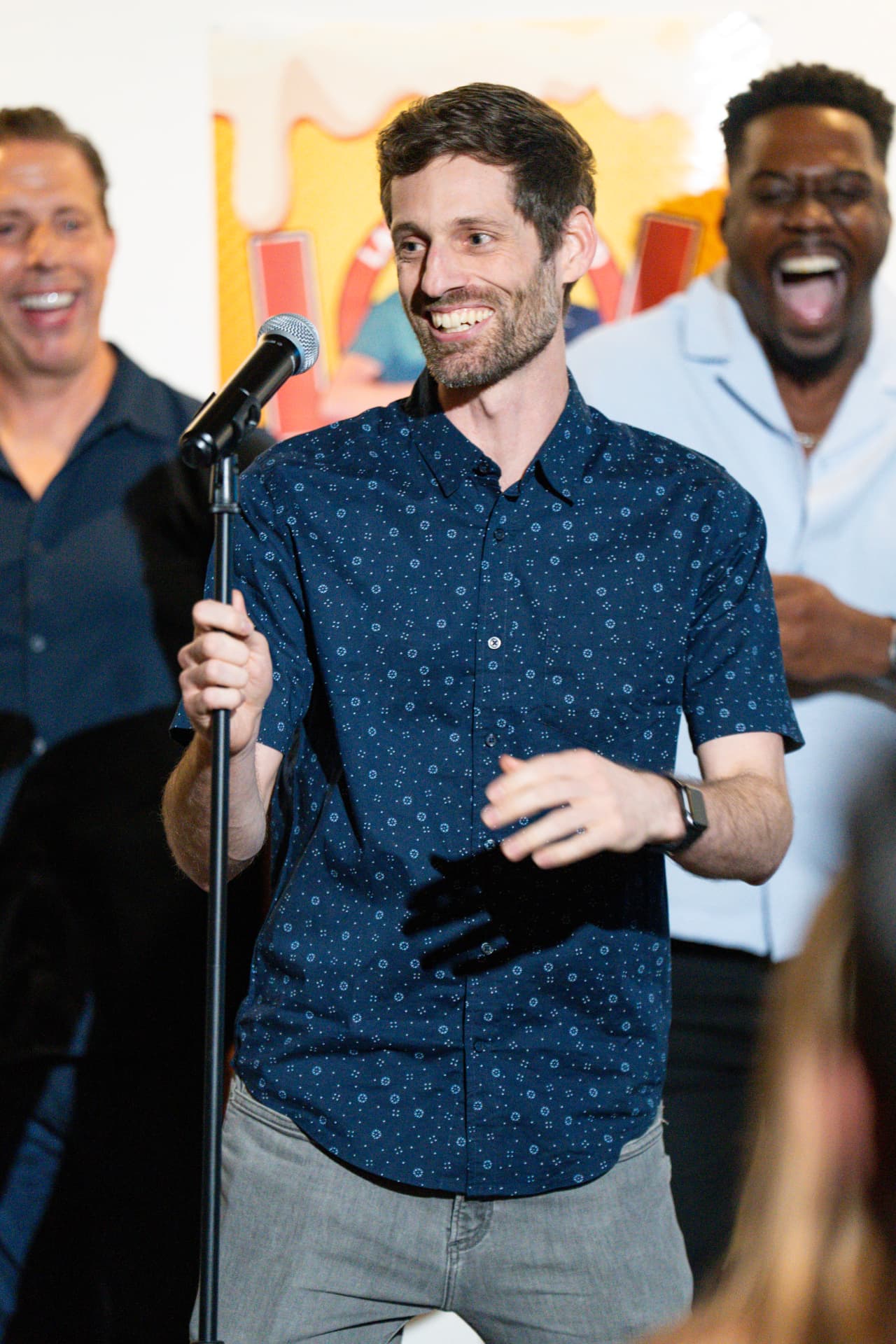 Comedian on stage with the lineup behind him