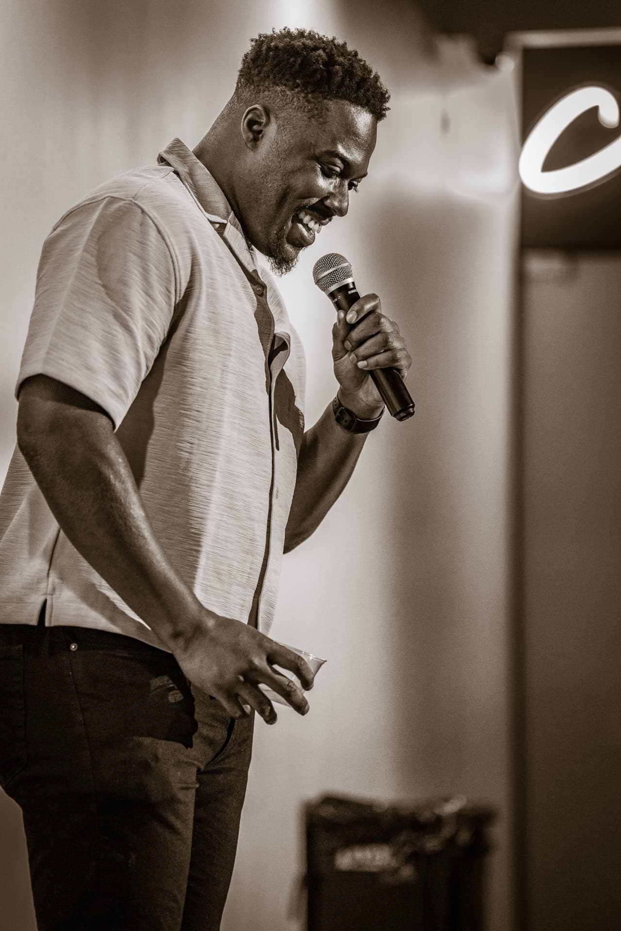 Sepia shot of a comedian doubled over laughing on stage