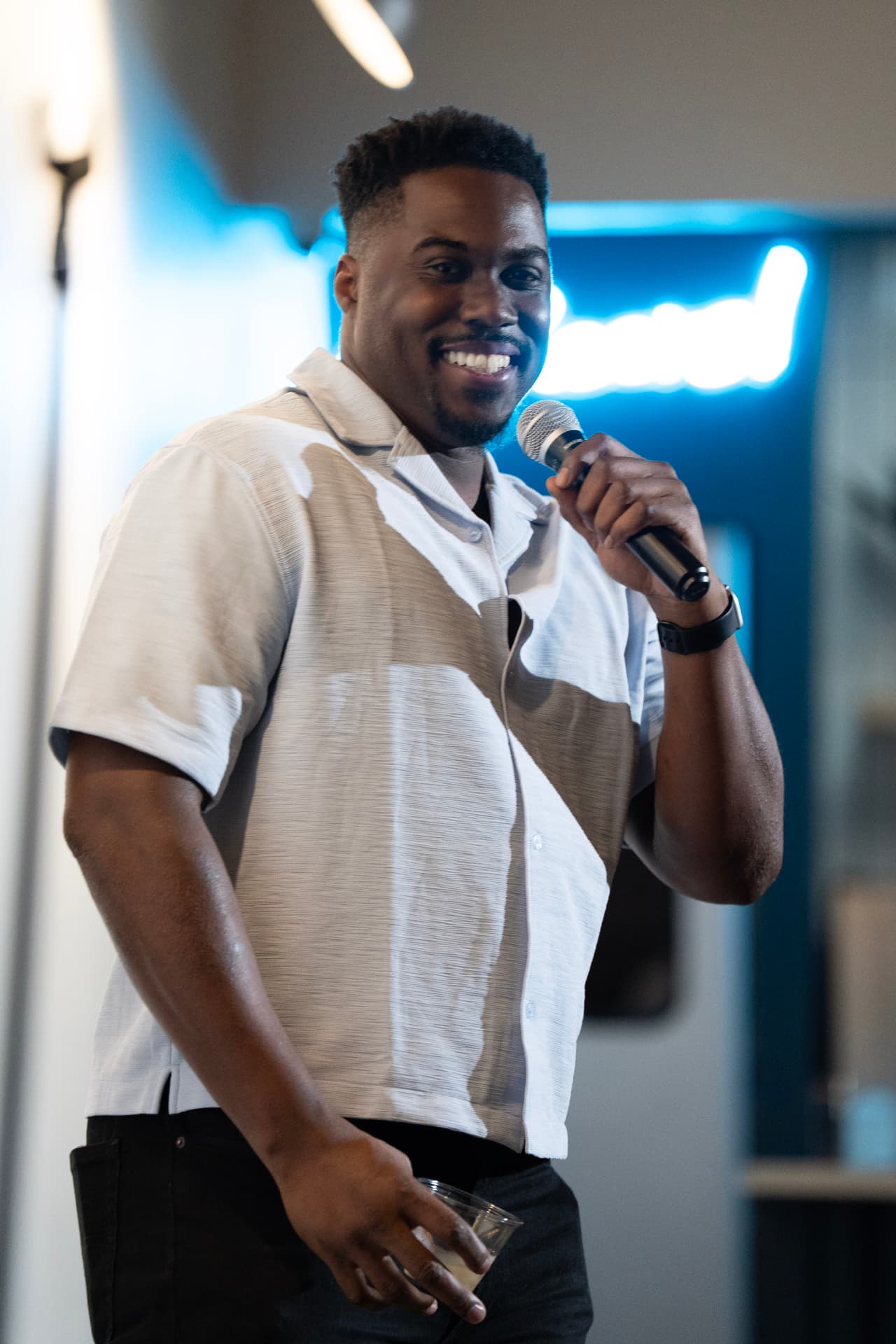 Comedian grinning with a drink in hand mid-set